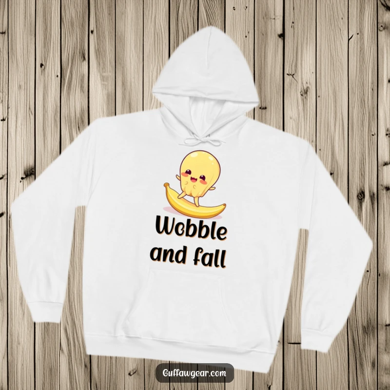 Funny hoodie with a wobbly jelly character dramatically slipping on a tiny banana peel, providing warmth and amusement.
